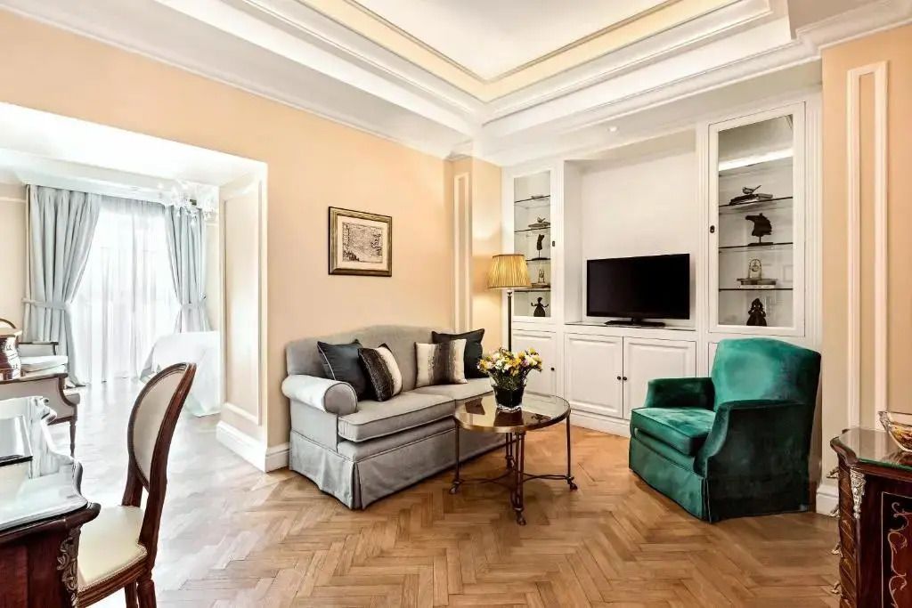 Gemütliche Sitzecke mit eleganten Möbeln und Flachbildfernseher in Suite.