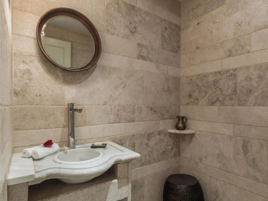 Modernes Badezimmer mit Steinfliesen und rundem Spiegel