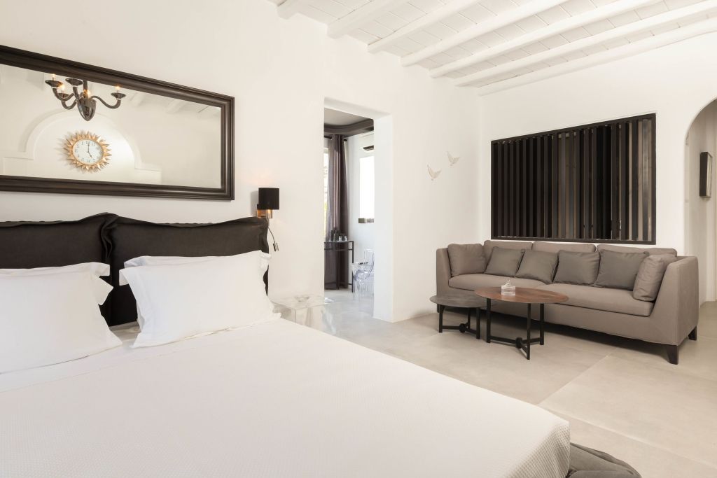 Helles Schlafzimmer mit gemütlicher Sitzecke und großen Spiegeln