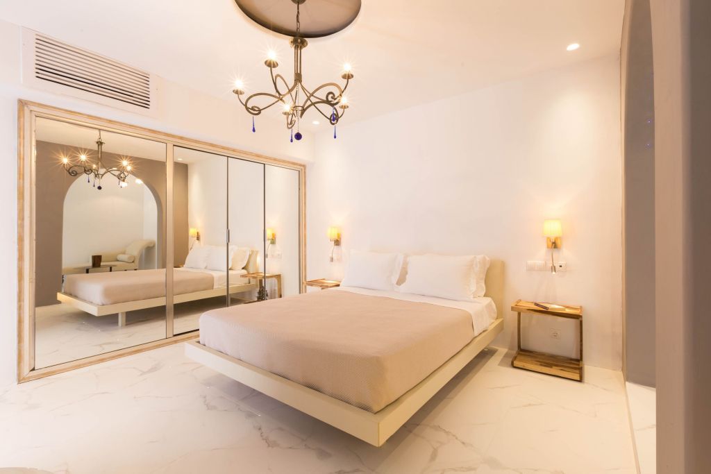 Helles Schlafzimmer mit Doppelbett und Kronleuchter in der Junior-Suite mit Meerblick