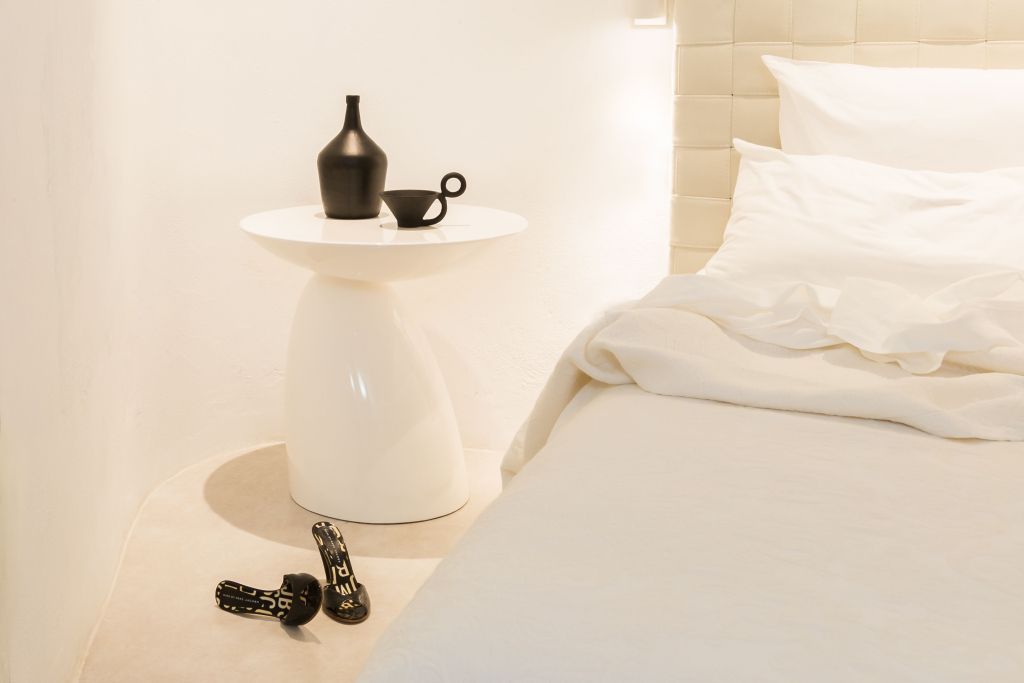 Weißer Beistelltisch und schwarze Dekorationen in elegantem Schlafzimmer