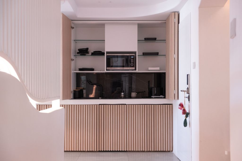 Kleine Küche in der Suite mit modernen Geräten und Holzlamellenfronten.