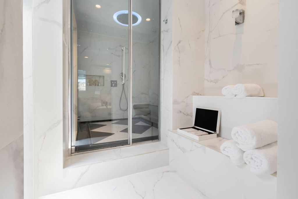 Marmorbadezimmer mit Regendusche und weißen Handtüchern