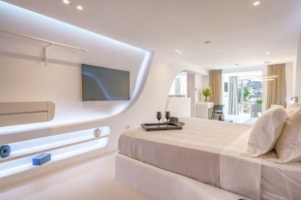 Luxuriöses Doppelzimmer mit modernen weißen Möbeln und indirekter Beleuchtung.