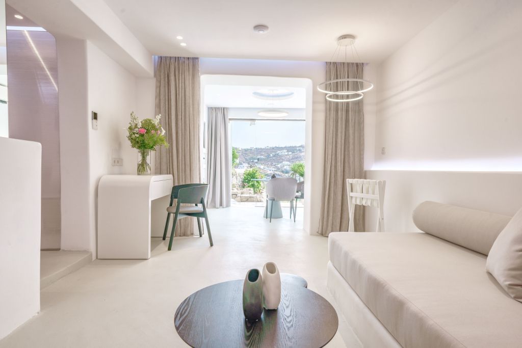Helles Wohnzimmer in Suite mit bequemen Sitzgelegenheiten und Blick auf das Meer.