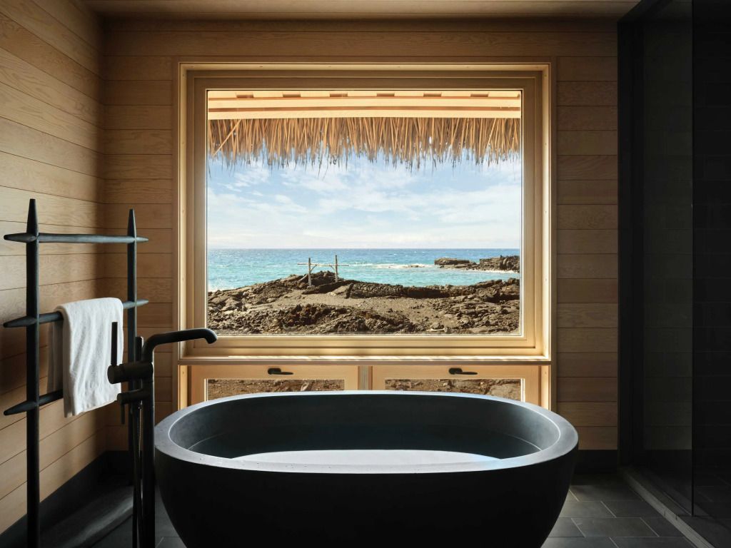 Badezimmer mit freistehender Badewanne und Blick auf Küstenlandschaft