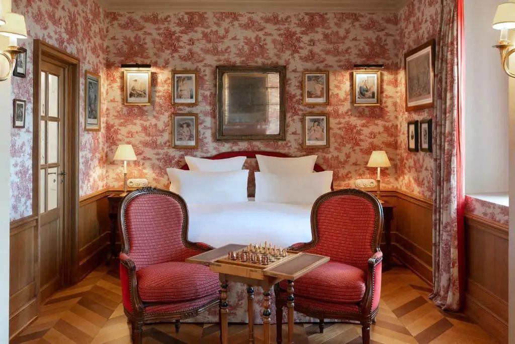 Elegantes Schlafzimmer mit roten Mustertapeten und antiken Möbeln