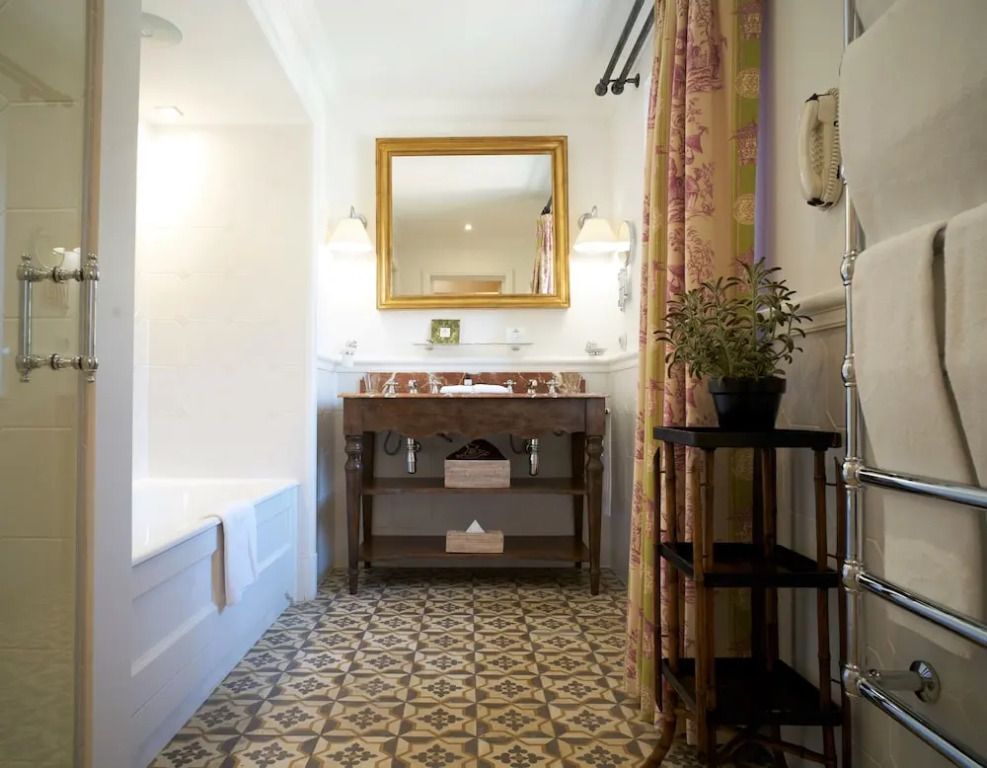 Elegantes Badezimmer mit antikem Waschtisch und gemustertem Fliesenboden