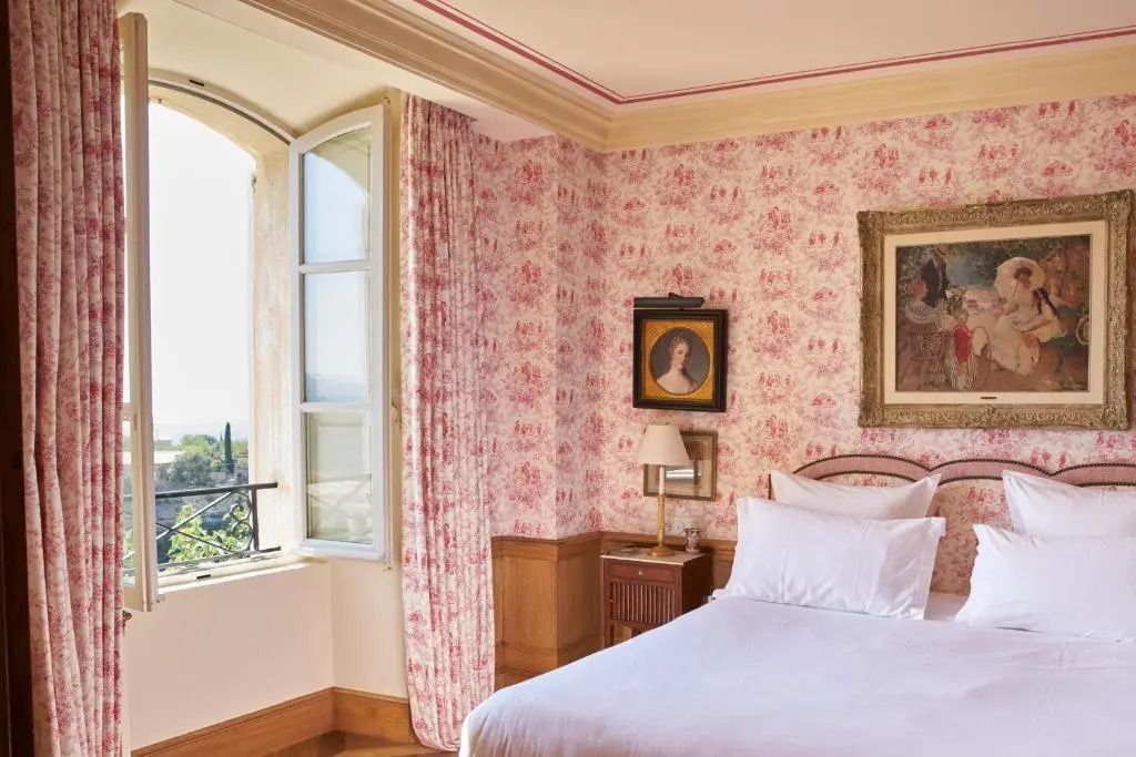 Schlafzimmer mit rosa Motiven und offenem Fenster mit schöner Aussicht