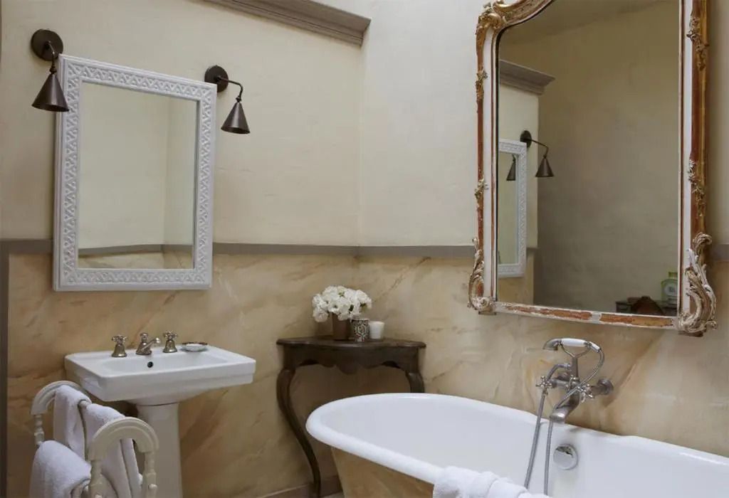 Elegantes Badezimmer mit freistehender Badewanne und antikem Spiegel.