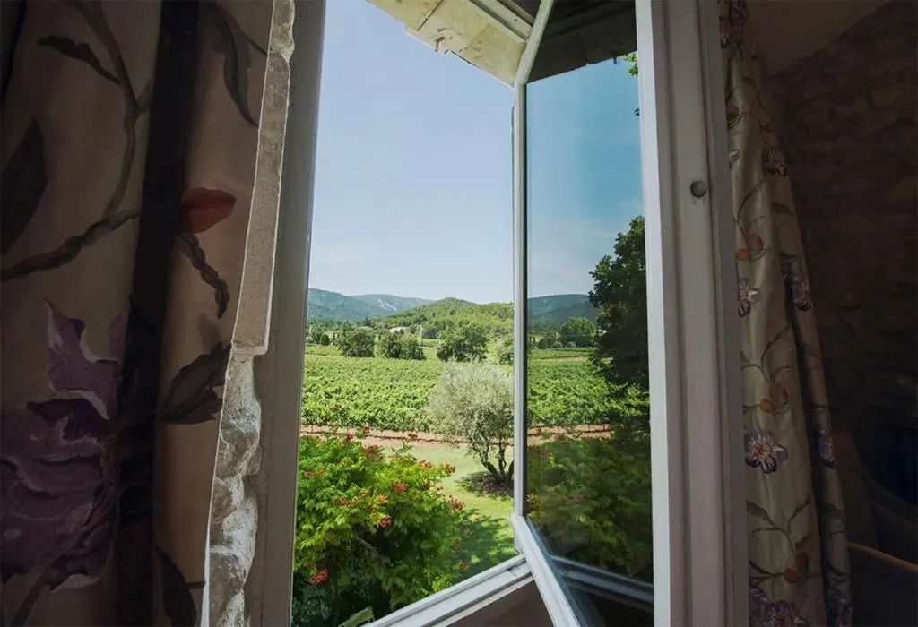 Maleblick aus dem Fenster über grüne Weinberge und Hügel.