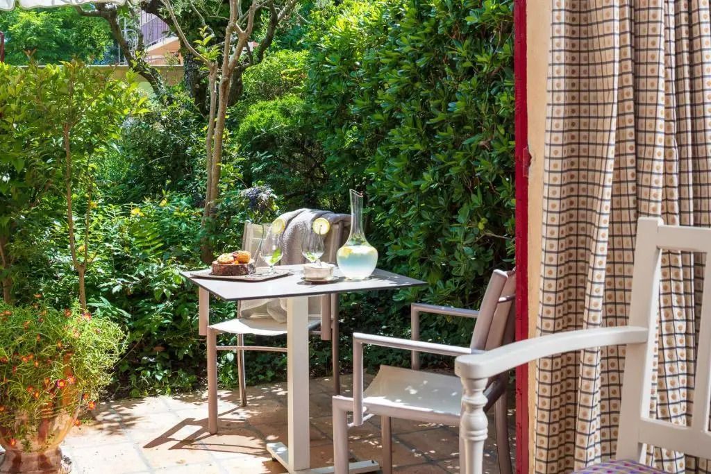 Idyllische Terrasse der Deluxe Junior-Suite mit Blick auf grünen Garten und Tisch für zwei.