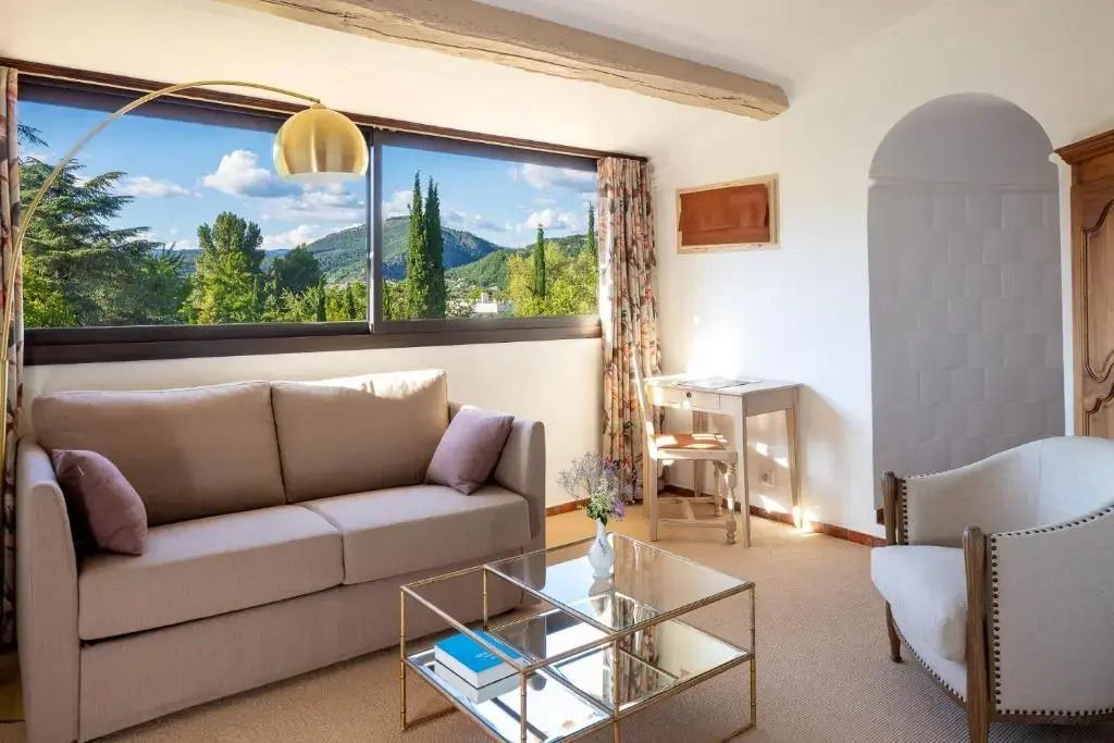 Junior-Suite mit Blick auf grüne Landschaften. Sofaecke vor großen Fenstern
