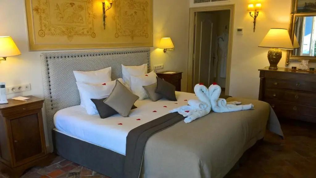 Romantisch dekoriertes Bett mit Handtuchschwänen und Rosenblättern im Zimmer
