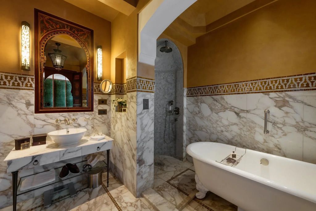 Elegantes Badezimmer der Agdal Suite mit Marmorwänden und freistehender Badewanne