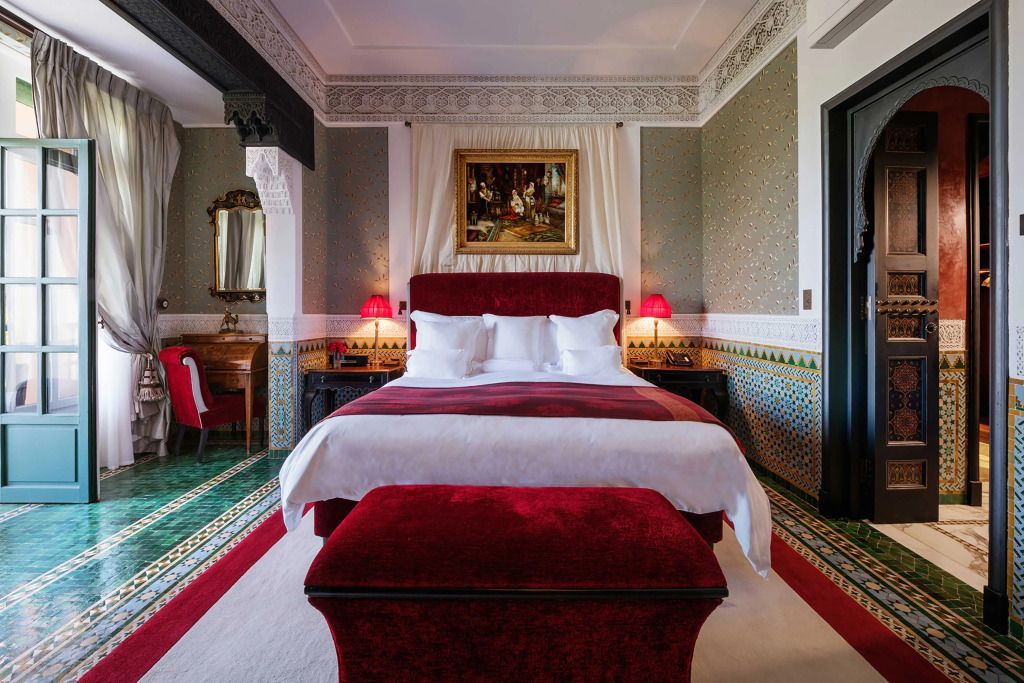 Luxuriöses Schlafzimmer der Al Mamoun Suite mit rotem Samtbett und stilvollem Dekor.