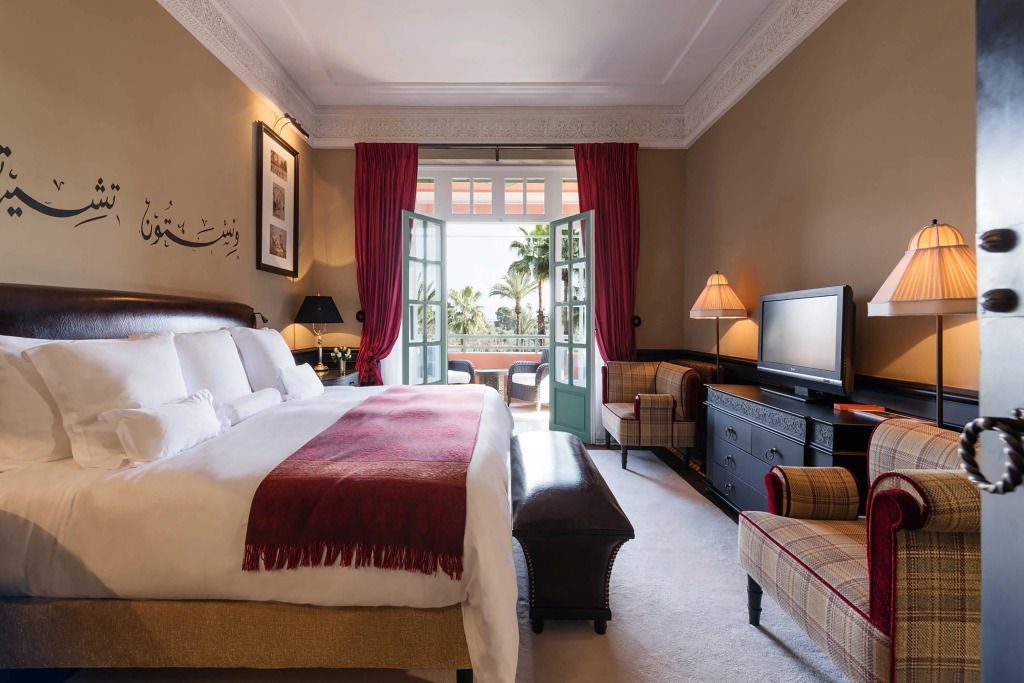 Elegantes Schlafzimmer mit großem Bett und Balkon mit Blick auf Palmen.