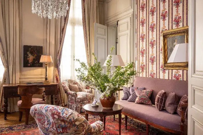 Sitzbereich der Deluxe Suite mit stilvollen Möbeln und Blumenarrangement