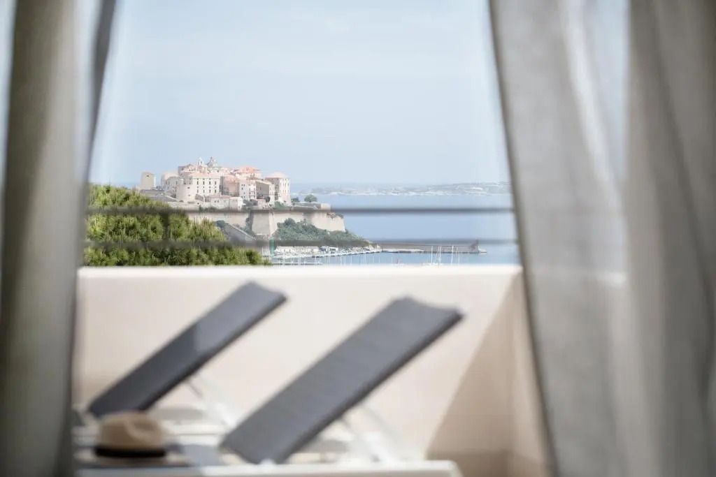 Sonnenliegen auf dem Balkon mit Meerblick und historische Gebäude im Hintergrund