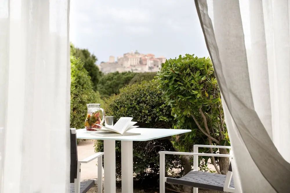 Terrasse mit Tisch und Stühlen Ausblick auf die Zitadelle von Calvi in der Ferne