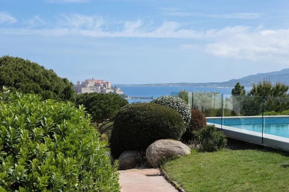 Garten mit Pool und Meerblick auf die Zitadelle von Calvi in der Ferne