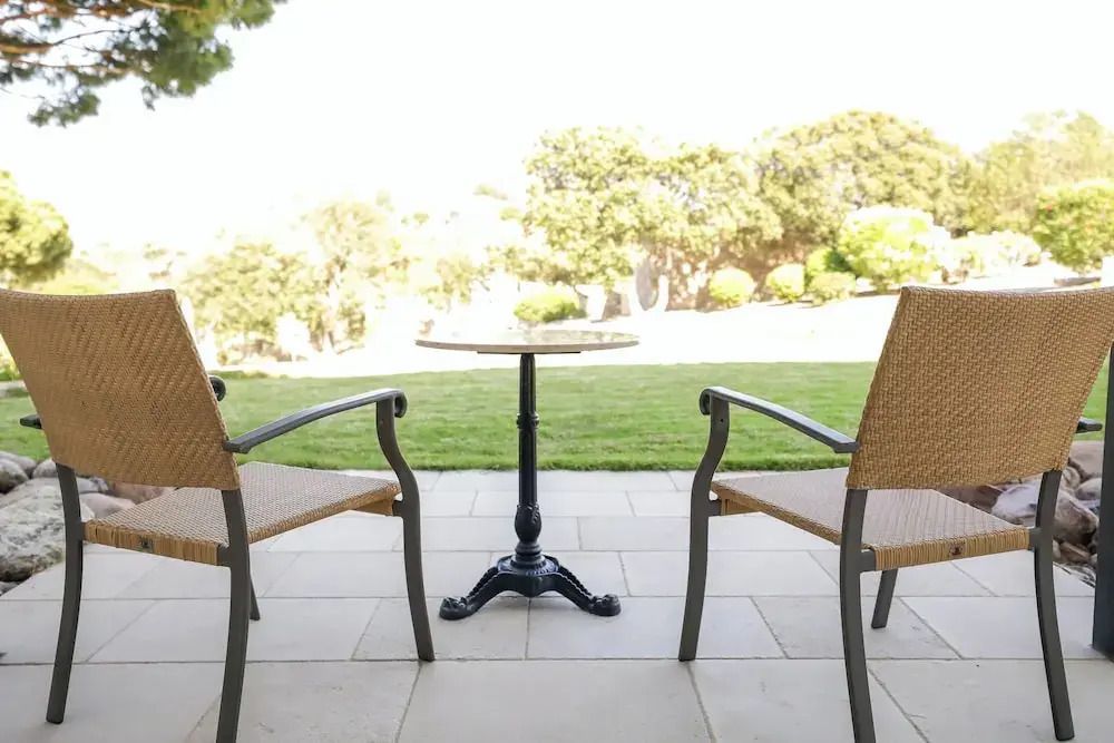 Terrasse mit Tisch und Stühlen und Blick auf gepflegten Rasen und Bäume