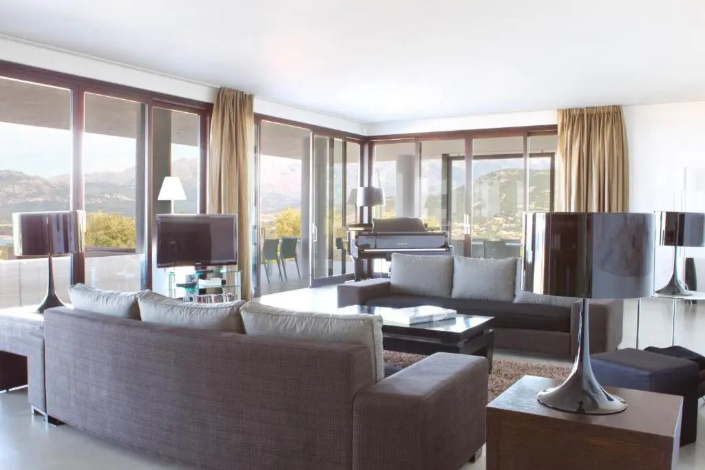 Helles Wohnzimmer mit Panoramafenstern und modernen Möbeln in einer Villa.