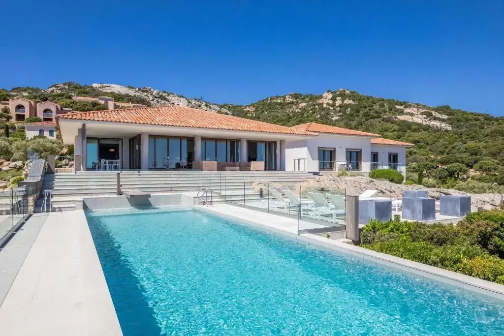 Außenansicht einer Villa mit großem Pool und Bergkulisse.