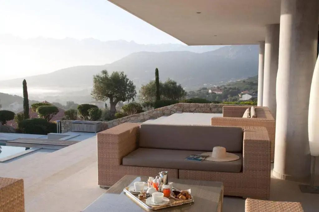 Terrasse mit Loungemöbeln und Berg- sowie Talblick.