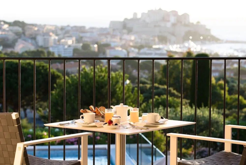 Balkon mit Tisch und Stühlen und Blick über Calvi bei Sonnenaufgang