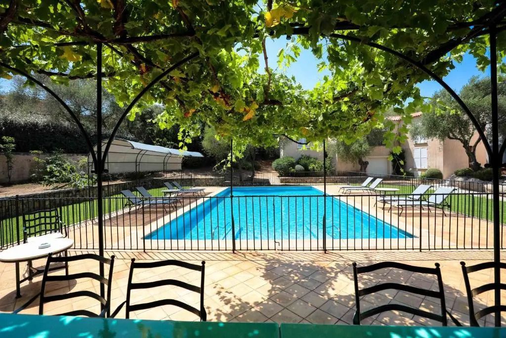 Blick von der Terrasse auf den Pool durch Bögen mit Weinreben