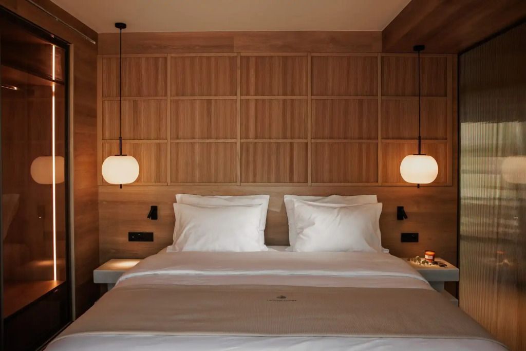 Bett mit weißen Kissen und Holzwänden in einem eleganten Zimmer