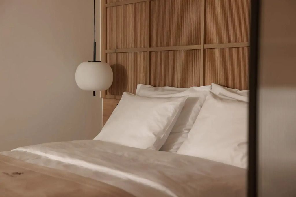 Detailaufnahme eines Bettes mit eleganter Holzwand und moderner Lampe