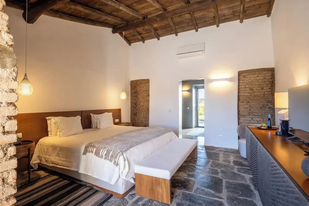 Junior-Suite mit rustikalem Holzgebälk und eleganter Steinfussboden