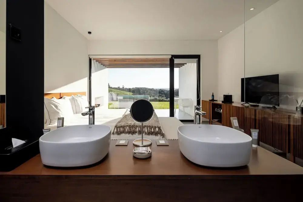 Moderne Suite mit Doppelwaschbecken und Blick auf die Landschaft.