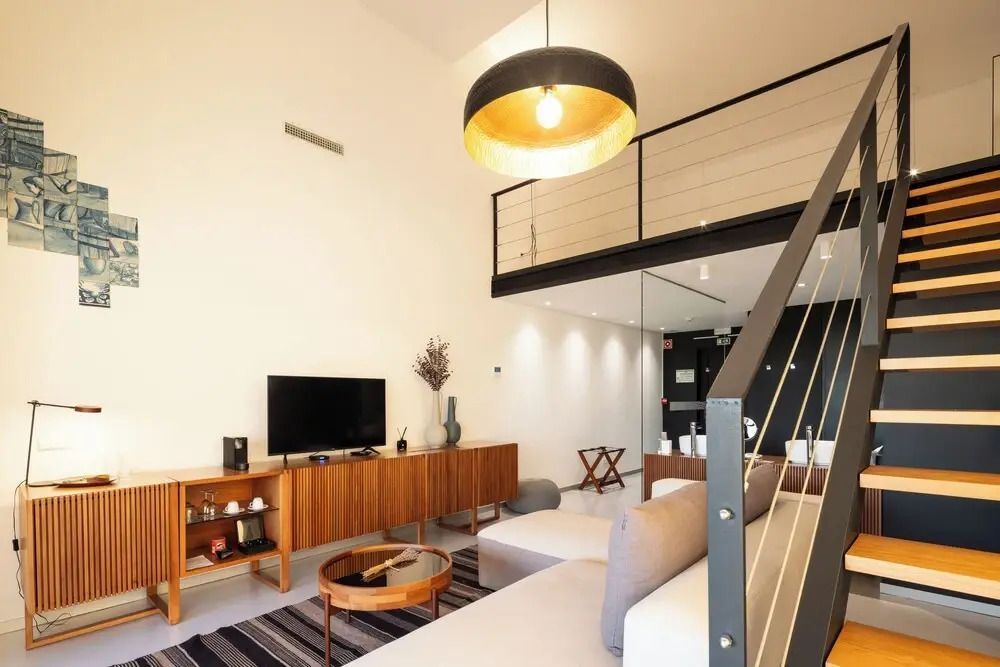 Wohnbereich mit Holzregal, Fernseher und Designer-Lampe unter offener Galerie.