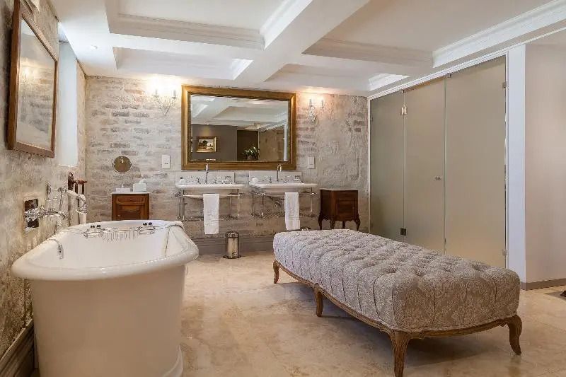 Elegantes Badezimmer mit freistehender Badewanne und Lehnstuhl im Lanzerac Hotel