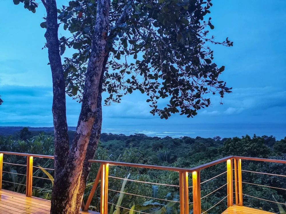 Abendlicher Blick von Terrasse mit beleuchtetem Geländer und Ozean im Hintergrund