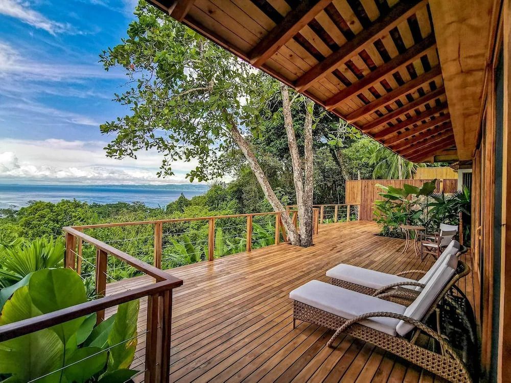 Große Holzterrasse mit Liegestühlen und Panoramaaussicht auf den Dschungel und Ozean