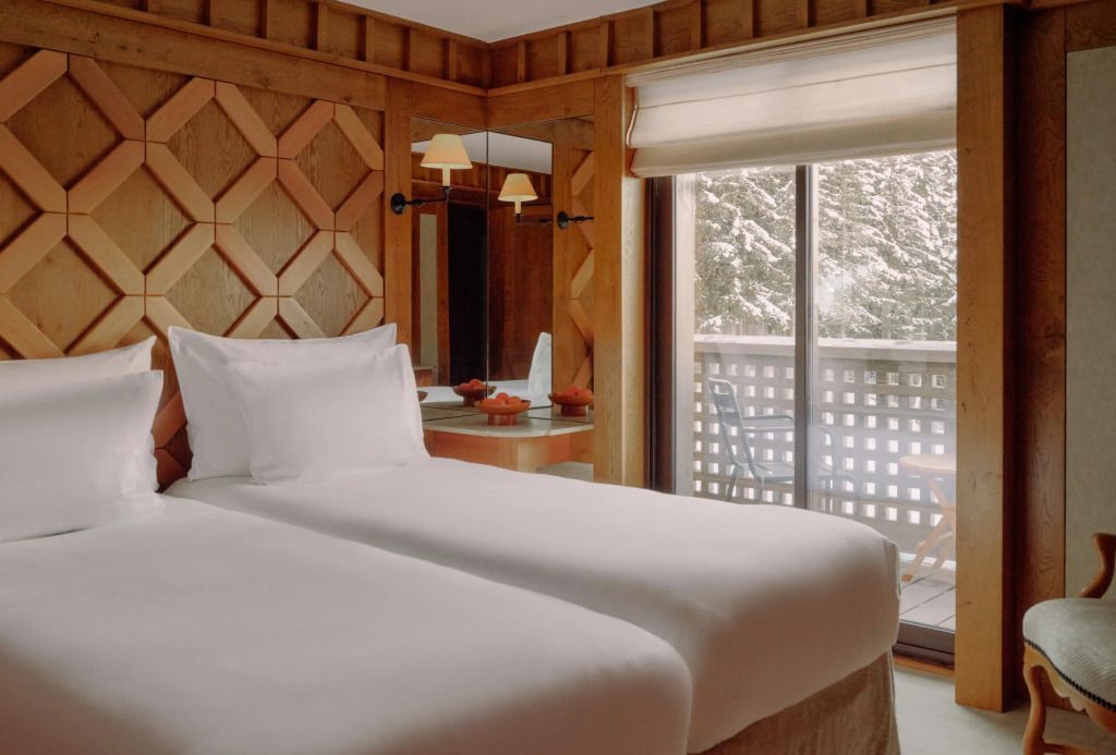 Doppelbett im Familien-Apartment mit Holzwandverkleidung und Blick auf den schneebedeckten Balkon.