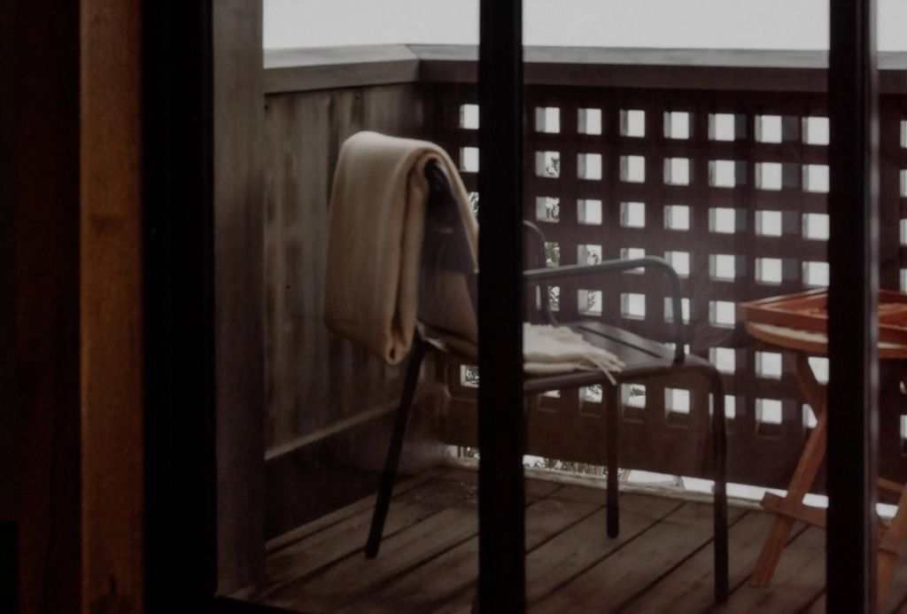 Kleiner privater Balkon mit Stuhl und Decke.