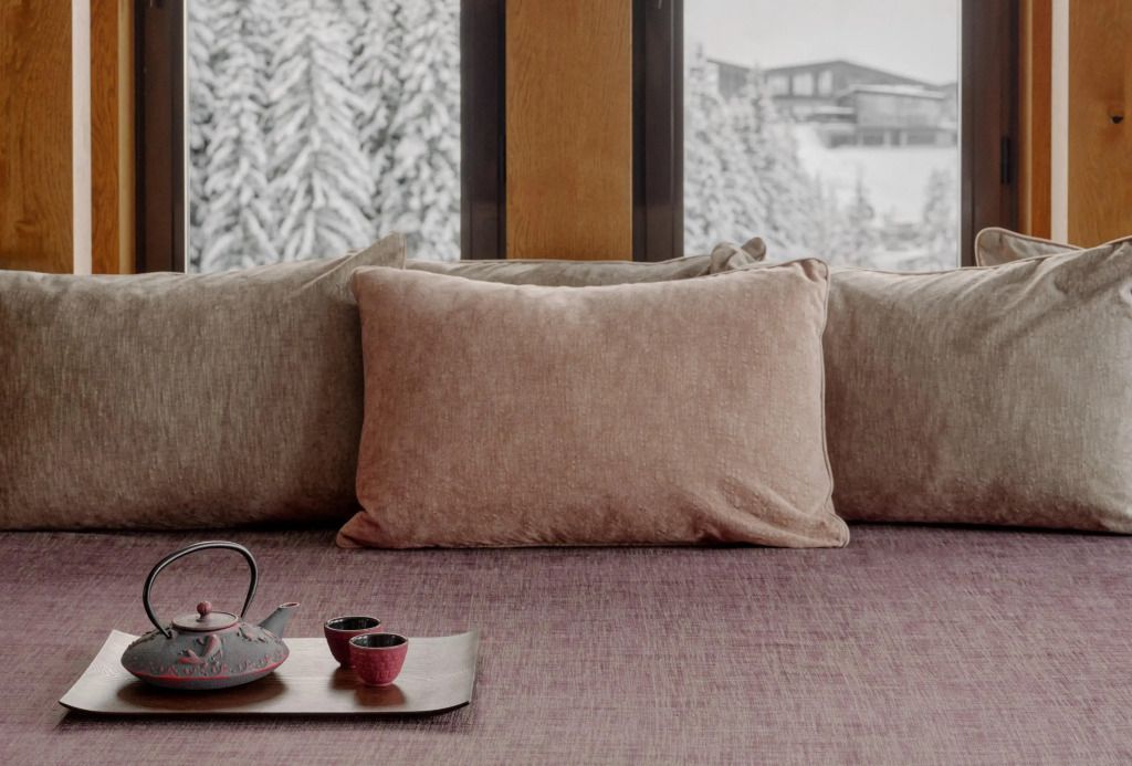 Detail eines gemütlichen Sitzbereichs mit winterlichem Ausblick im Aman Le Mélézin