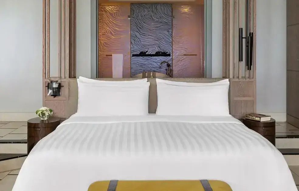 Modernes Schlafzimmer mit großem Doppelbett und dekorativer Glaswand.