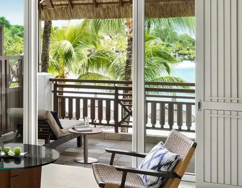 Balkon mit tropischem Ausblick auf Palmen und Meer.