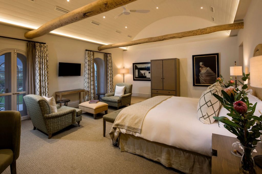 Elegantes Schlafzimmer mit Holzbalken und gemütlicher Sitzecke im Leeu Estate