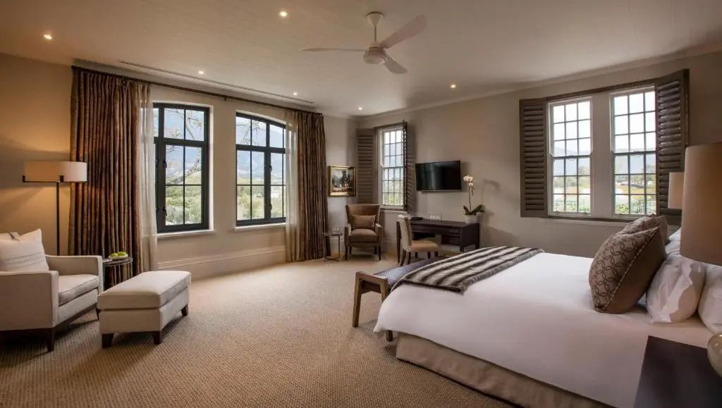 Helles Deluxe Doppelzimmer mit großen Fenstern und Blick auf die Landschaft.