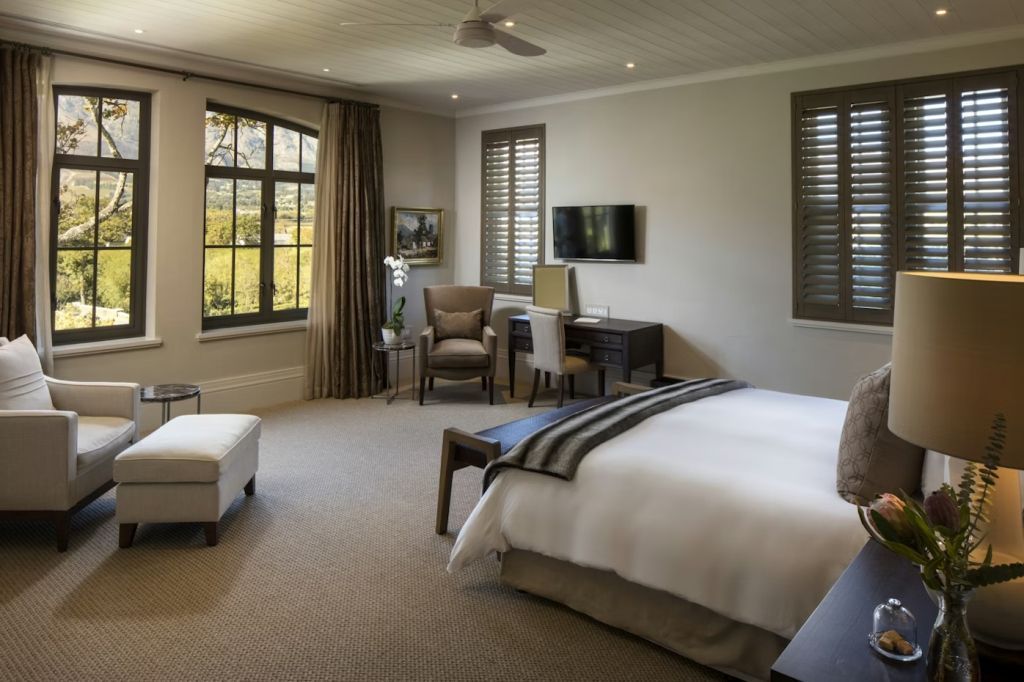 Helles Schlafzimmer im Protea House mit großem Bett, Sitzbereich und Fenstern.