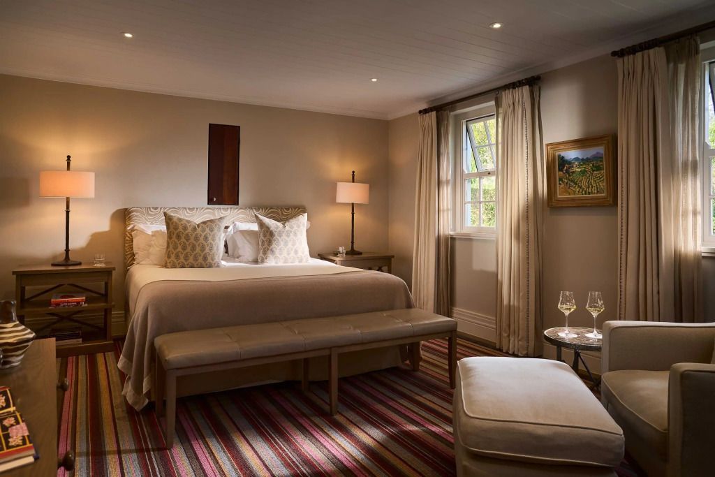 Gemütliches Schlafzimmer mit großem Bett, warmes Licht und eleganter Teppich.