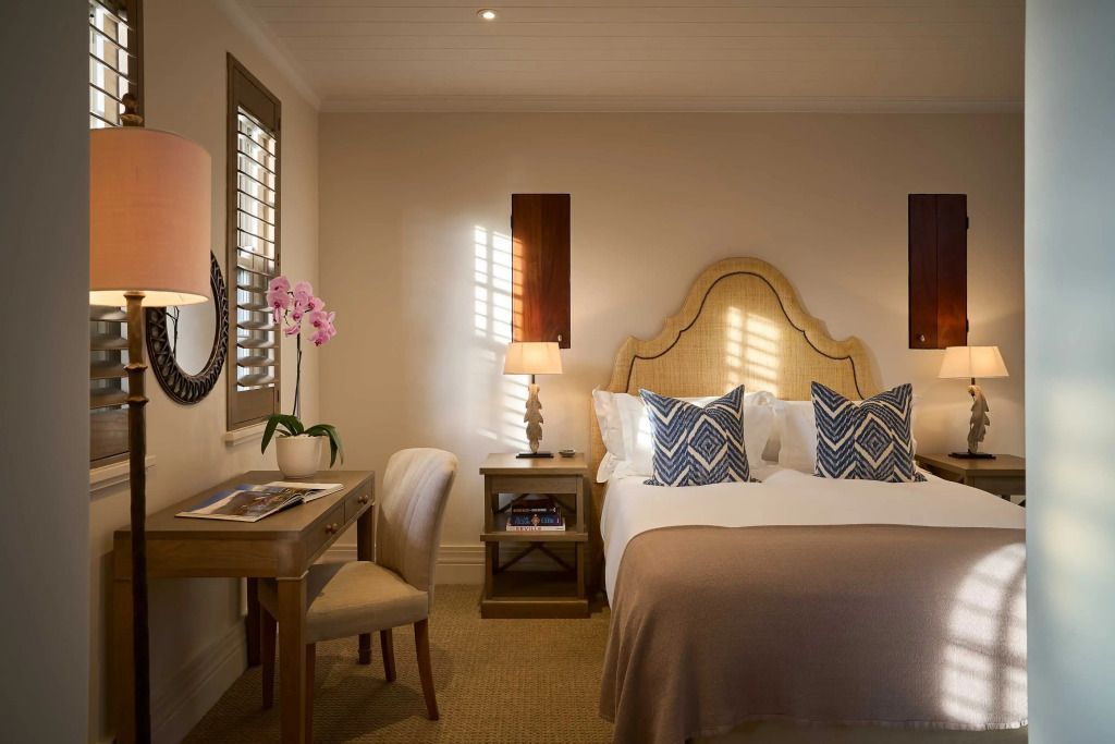 Doppelzimmer mit Schreibtisch, Sessel und eleganter Beleuchtung.