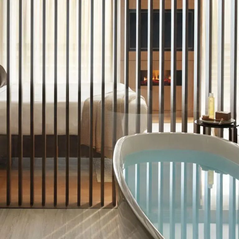 Freistehende Badewanne und Bett mit Trennwand in einer Suite